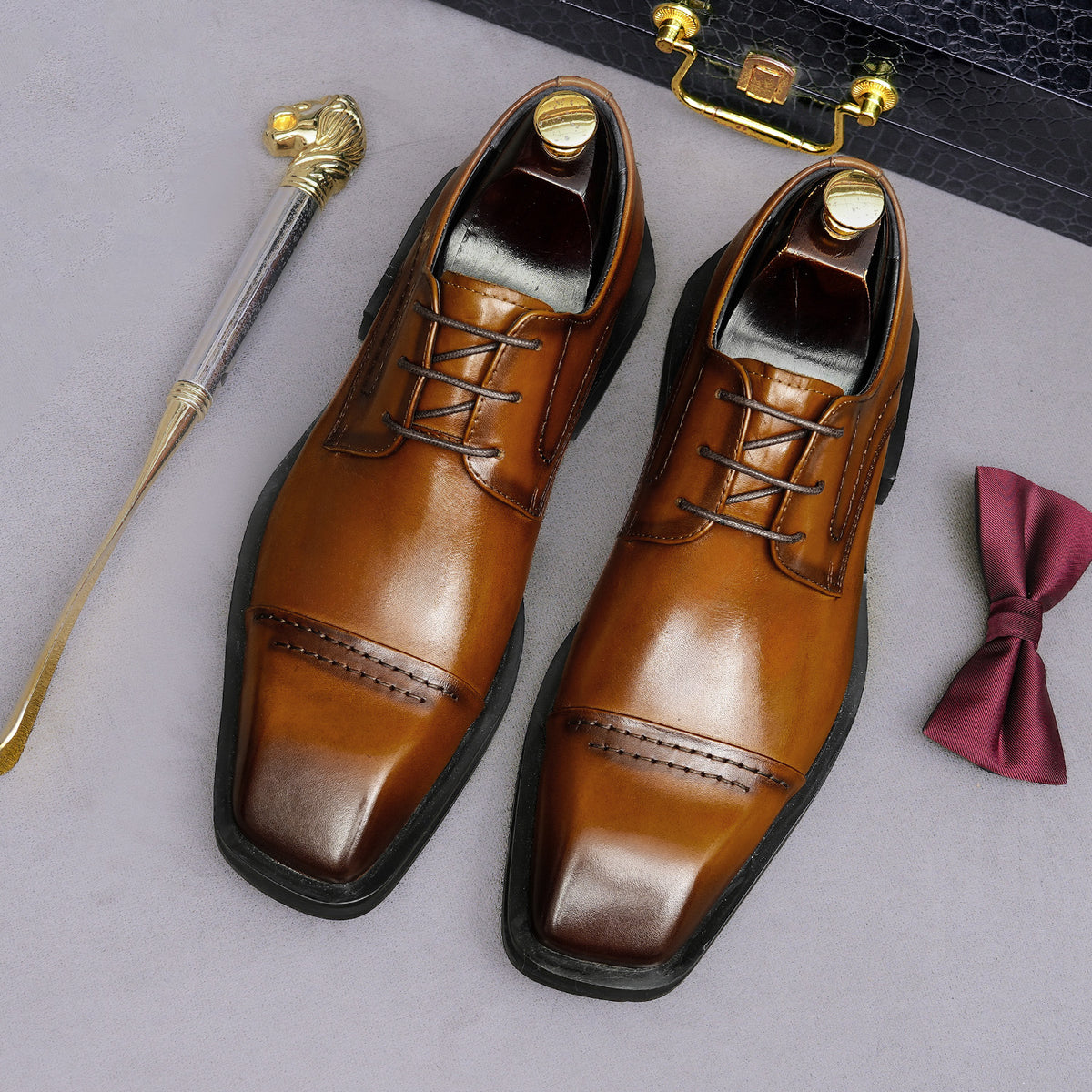Men's brown leather lace-up derby dress shoes, pointed toe with polished finish and stitching.