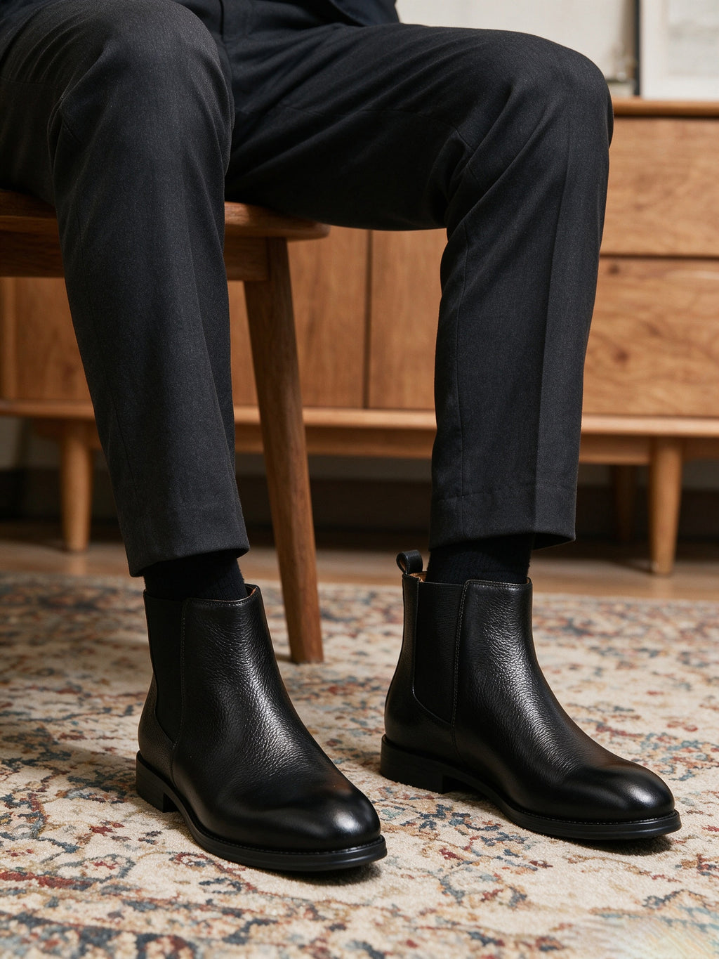 Black Chelsea dress boots on feet with elastic side panels and squared heel sole