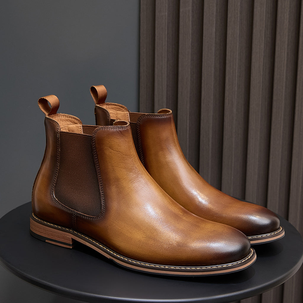 Pair of brown Chelsea dress boots with side elastic panels, pull tabs, and stitched sole