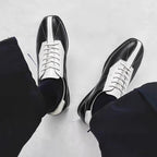Black leather low-top sneakers with white side panels and lace-up front.