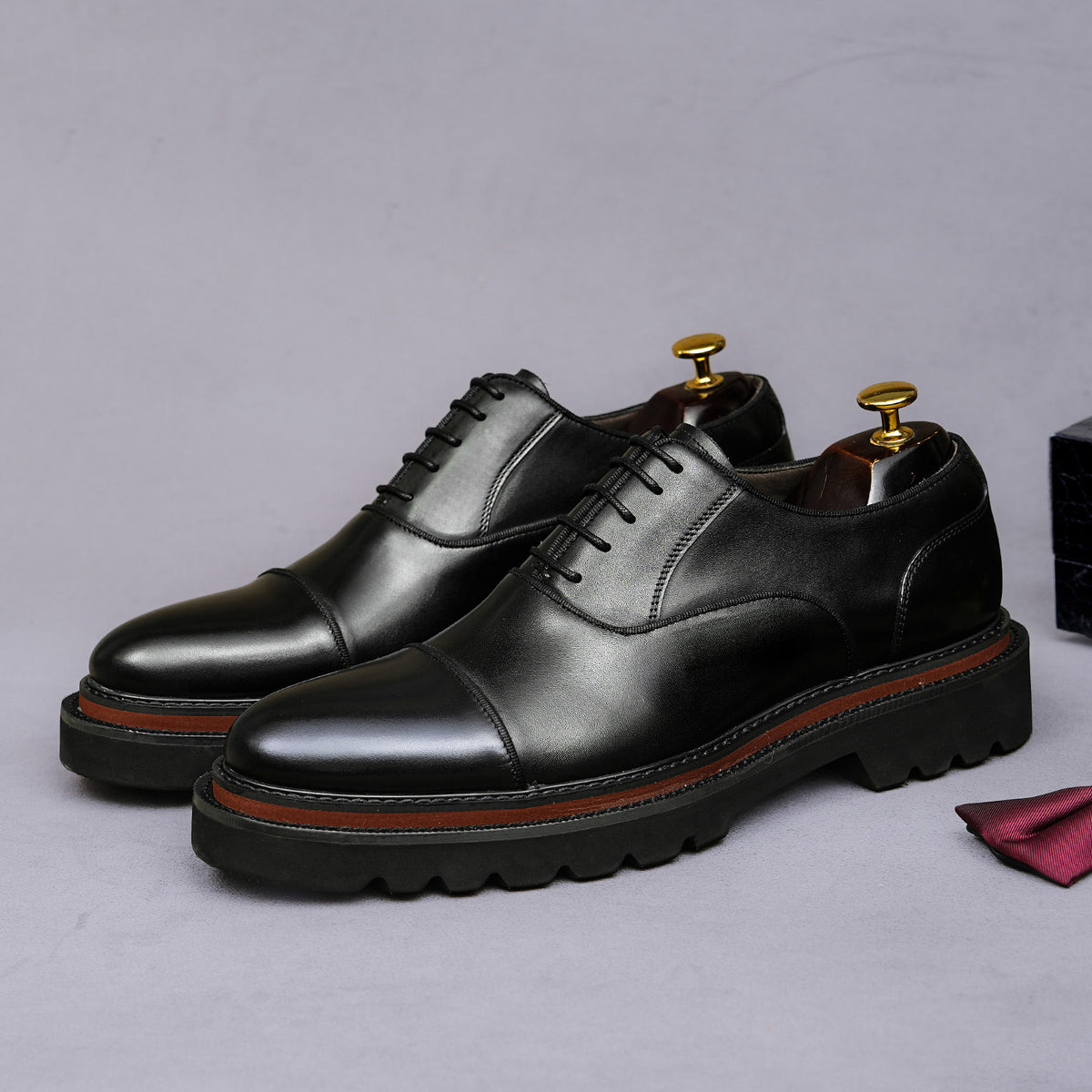 Black lace-up oxford shoes with raised chunky sole and contrast orange welt