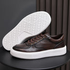Men's dark brown leather sneaker showing underside outsole tread with white rubber edge