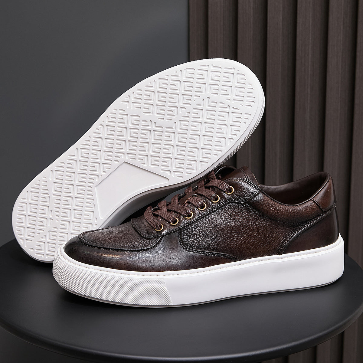 Men's dark brown leather sneaker showing underside outsole tread with white rubber edge