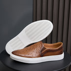 Brown leather slip-on sneaker showing treaded outsole with white rubber edges