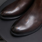 Close-up of dark brown chelsea dress boot pointed toe and stitched edge