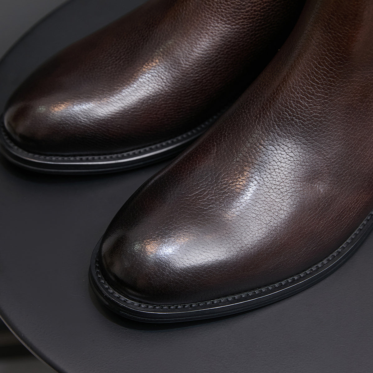 Close-up of dark brown chelsea dress boot pointed toe and stitched edge