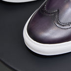 Dark purple leather sneaker toe with stitched seam and textured white sole