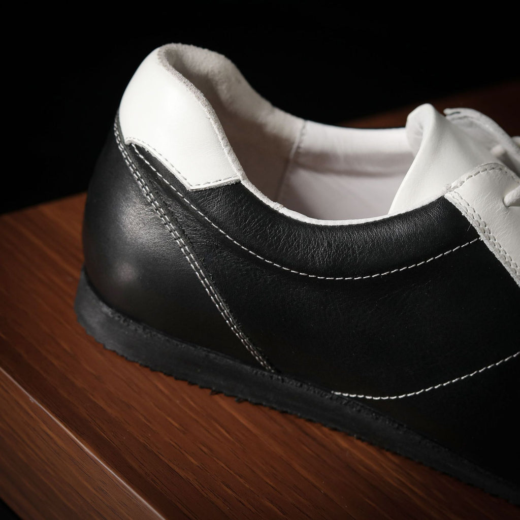 Close-up of black and white leather sneaker heel with side stitching and rubber sole.