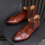 Brown pointed-toe Chelsea dress boots with elastic side panels and low stacked sole