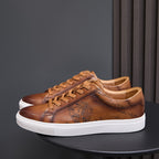 Men's tan leather sneakers with lace-up front, embossed details, and white rubber sole