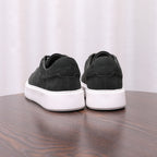 Pair of men's dark leather sneakers with white midsoles and lace-up uppers