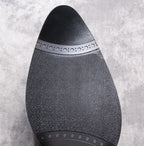 Black leather Chelsea boot outsole with textured tread and patterned edge trim