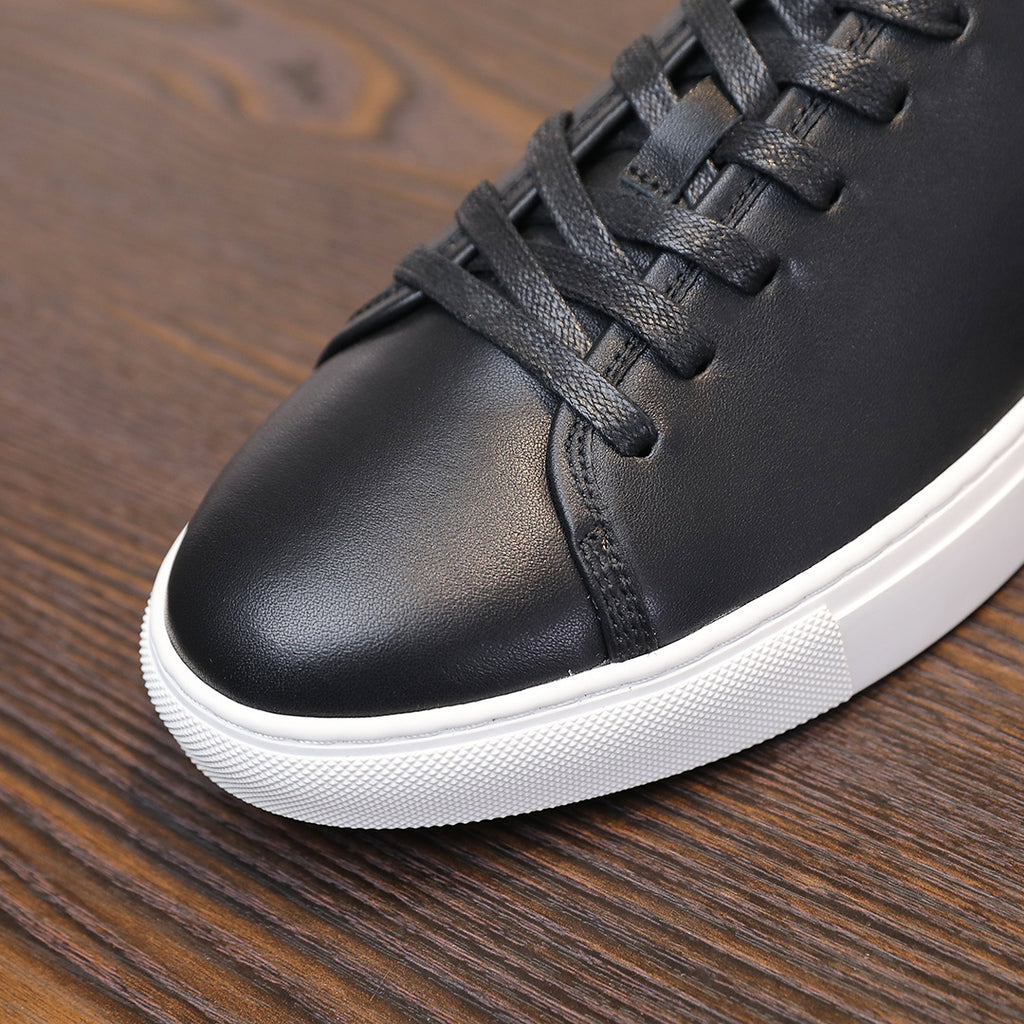 Black leather lace-up sneaker close-up with white platform sole edge.