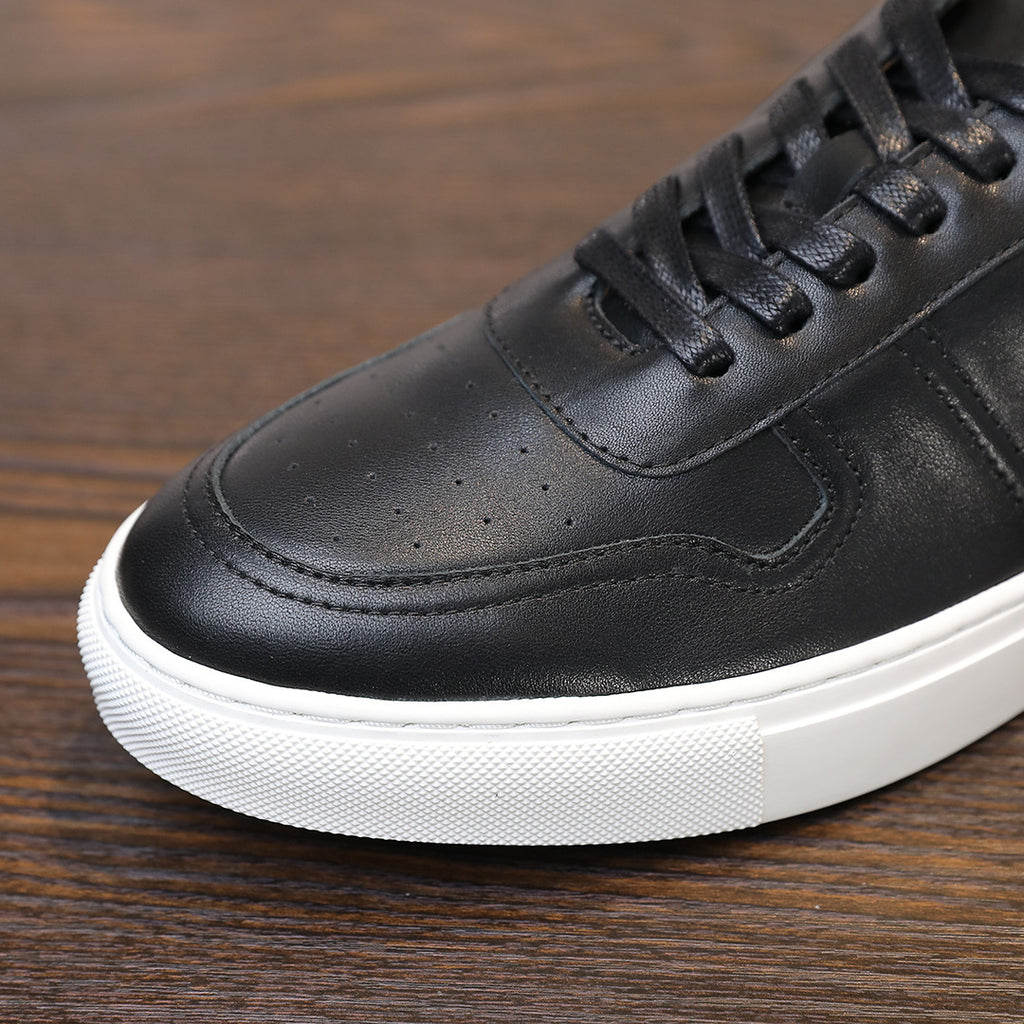 Close-up of black leather sneaker toe and laces, with white rubber sole