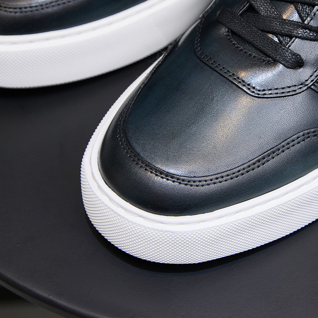 Dark blue leather sneaker toe and lace area with stitched seams, white platform sole.