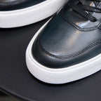 Dark blue leather sneaker toe and lace area with stitched seams, white platform sole.