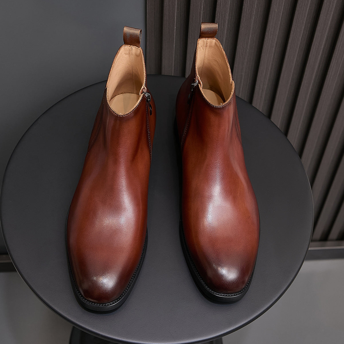 Pair of men's pointed-toe leather dress boots with side zip, brown leather and black sole.