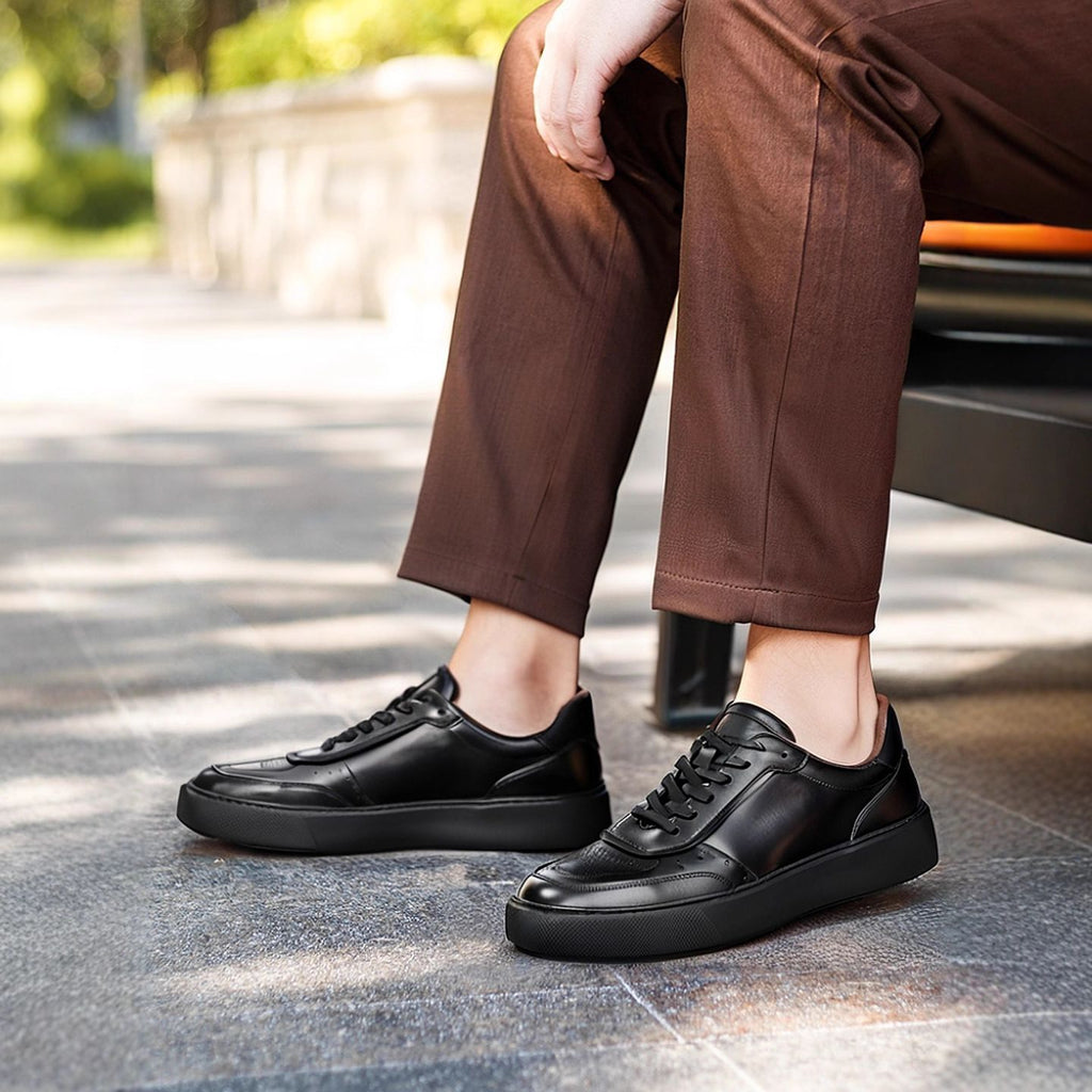 Black leather sneakers worn with brown pants, lace-up design and textured rubber sole
