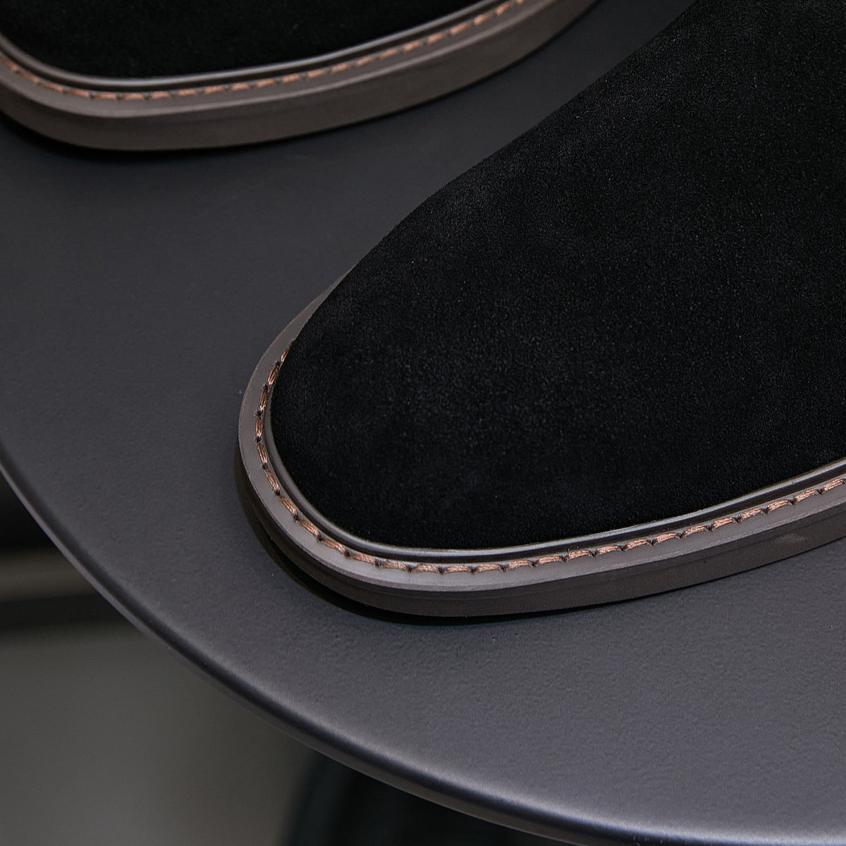 Black chukka boot toe and sidewall with contrast stitching along the sole edge
