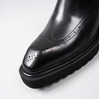 Black leather dress boot toe with perforated brogue detailing and stitched edge