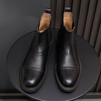 Pair of black Chelsea dress boots with pointed toes, elastic sides, and stitched welt detail.