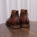 Brown leather pointed-toe ankle dress boots with side zippers, back view.
