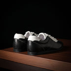 Black and white leather sneakers, rear view showing heel and collar contours.