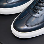 Blue leather lace-up sneaker close-up, black laces and white textured sole