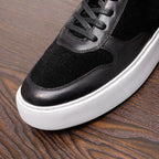 Black leather sneakers close-up: textured suede panel, lace eyelets, white midsole