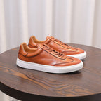 Brown leather low-top sneakers with lace-up, white sole, and stitched overlay panels