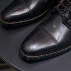 Black pointed-toe leather ankle boot detail, lace-up front and stitched panels with side zipper