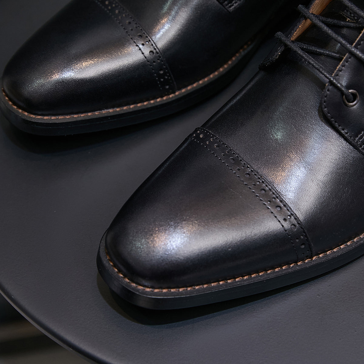 Black pointed-toe leather ankle boot detail, lace-up front and stitched panels with side zipper