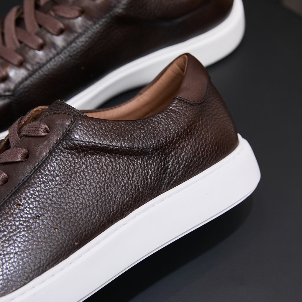 Dark brown leather sneaker side profile with lace-up and white rubber sole