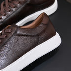 Dark brown leather sneaker side profile with lace-up and white rubber sole