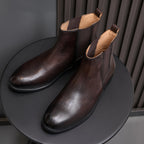 Pointed-toe Chelsea boots, dark brown, angled pair view with pull tabs and lining