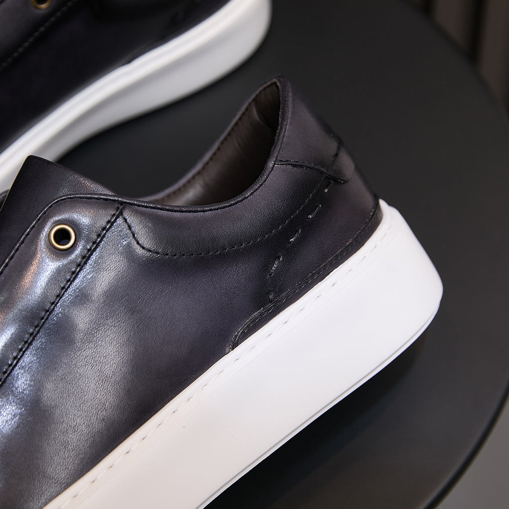 Close-up of black leather sneaker upper with side stitching and small eyelet