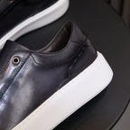 Close-up of black leather sneaker upper with side stitching and small eyelet