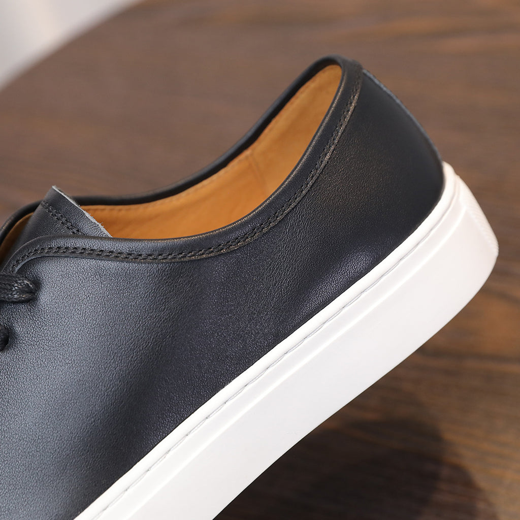 Black leather sneaker with padded collar and tan inner lining, side view.