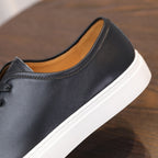 Black leather sneaker with padded collar and tan inner lining, side view.