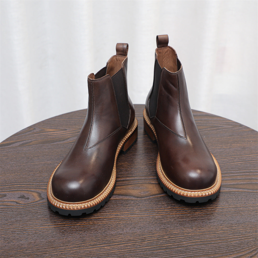 Pair of dark brown Chelsea dress boots, pointed toe, elastic side panels, on table