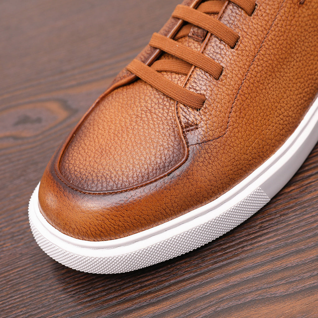 Brown leather lace-up sneaker with textured upper, stitching, and white rubber sole