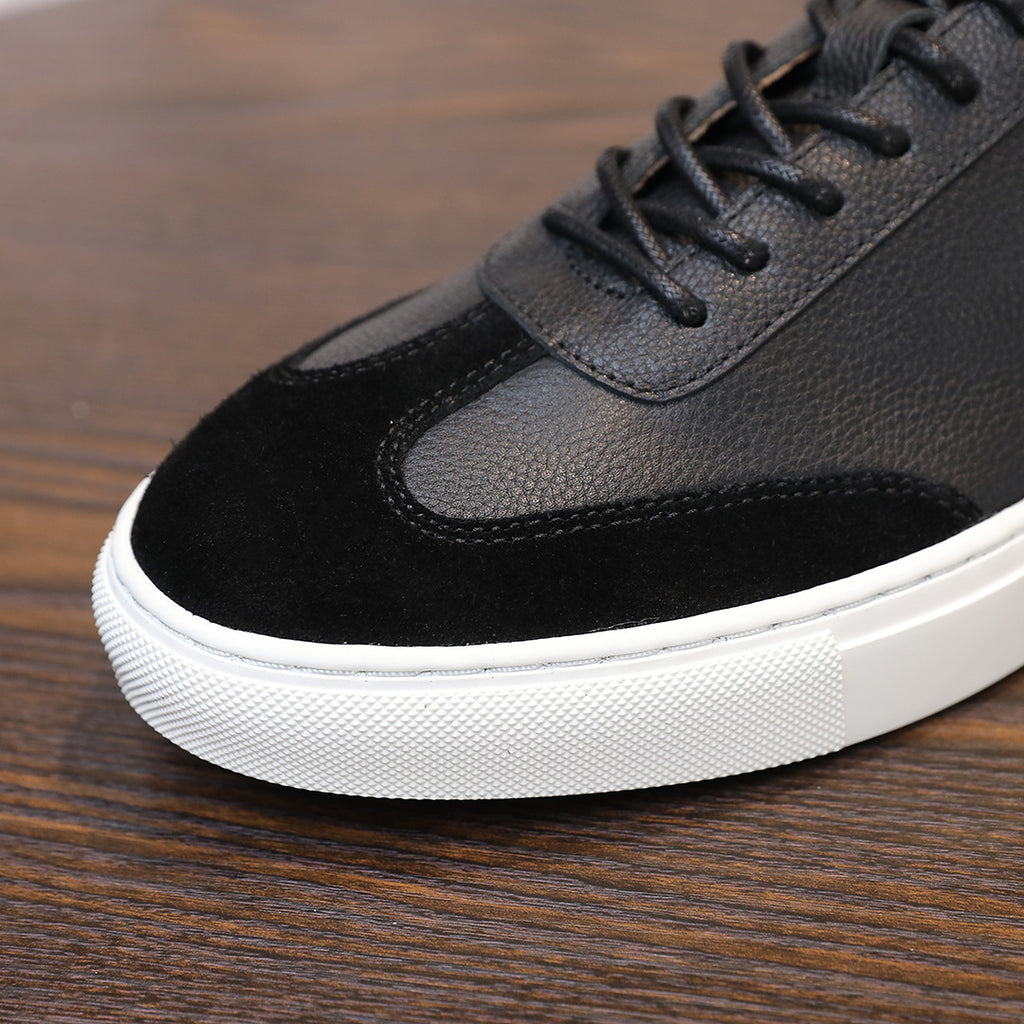 Men's black leather sneakers, lace-up with textured suede toe panel and white sole.