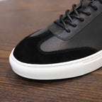 Men's black leather sneakers, lace-up with textured suede toe panel and white sole.