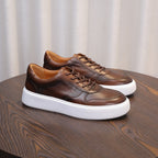 Dark brown leather low-top lace-up sneakers in side-by-side view with white outsole