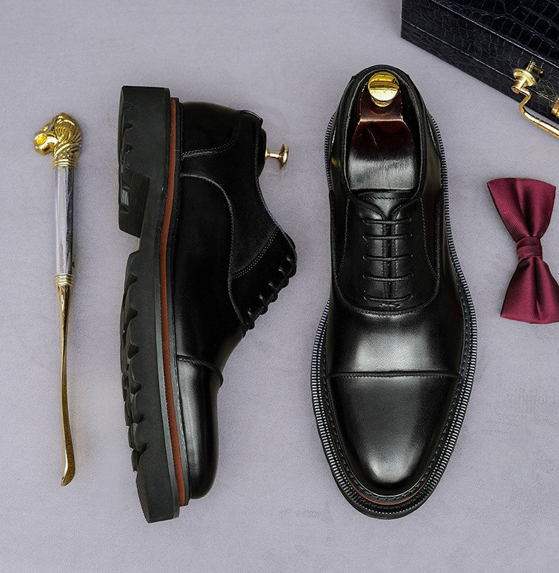Black lace-up oxford shoes with brogue detailing and chunky lug sole, side profile.