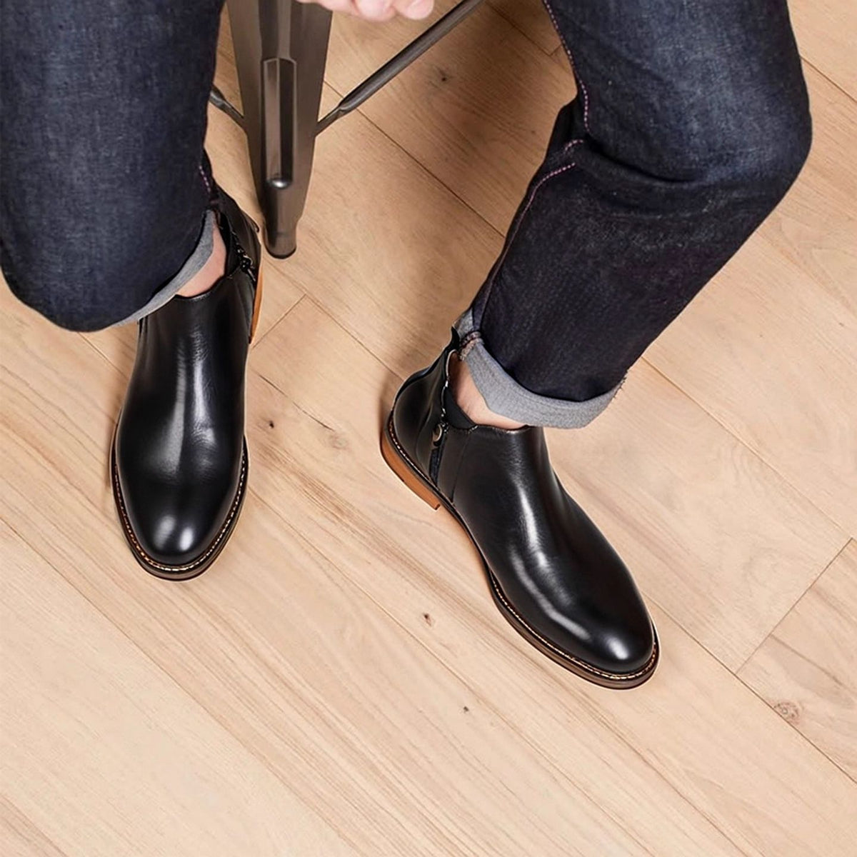 Black leather pointed-toe dress boots with side zipper, worn over jeans.
