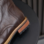 Dark brown leather boot heel quarter with tan welt, stacked sole edge, and lug tread