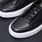 Men's genuine leather sneakers in black, close-up of laces, stitching, and white sole.
