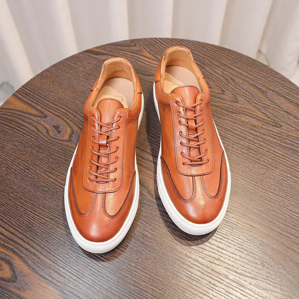 Brown leather sneakers pair with lace-up front, white soles, and curved toe caps