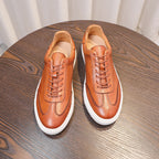 Brown leather sneakers pair with lace-up front, white soles, and curved toe caps